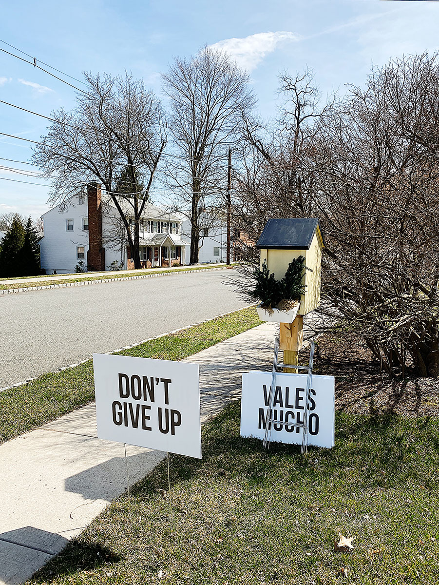 A yard sign saying "Don't Give Up" planted in the grass.
