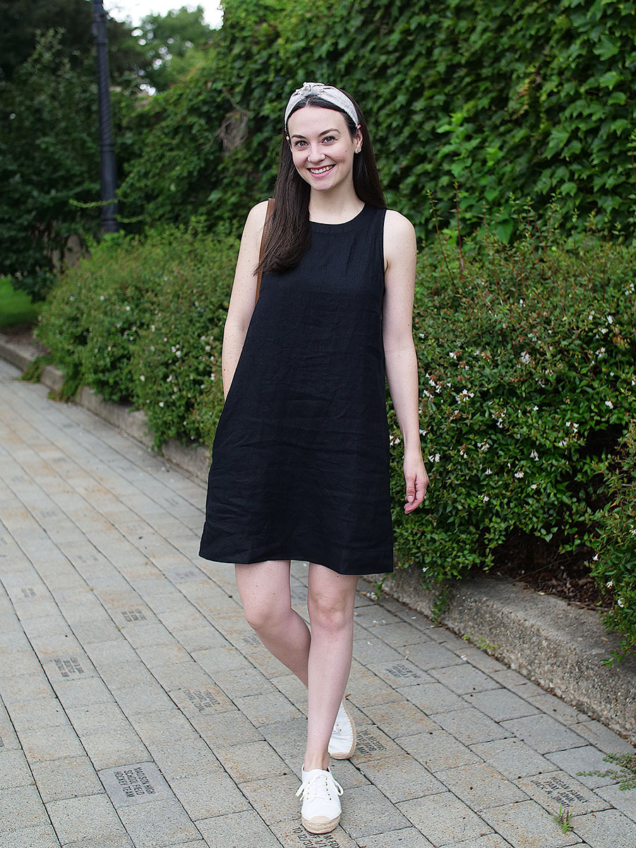 Carly Heitlinger stands in front of a wall of ivy while wearing a black linen dress from J. Crew