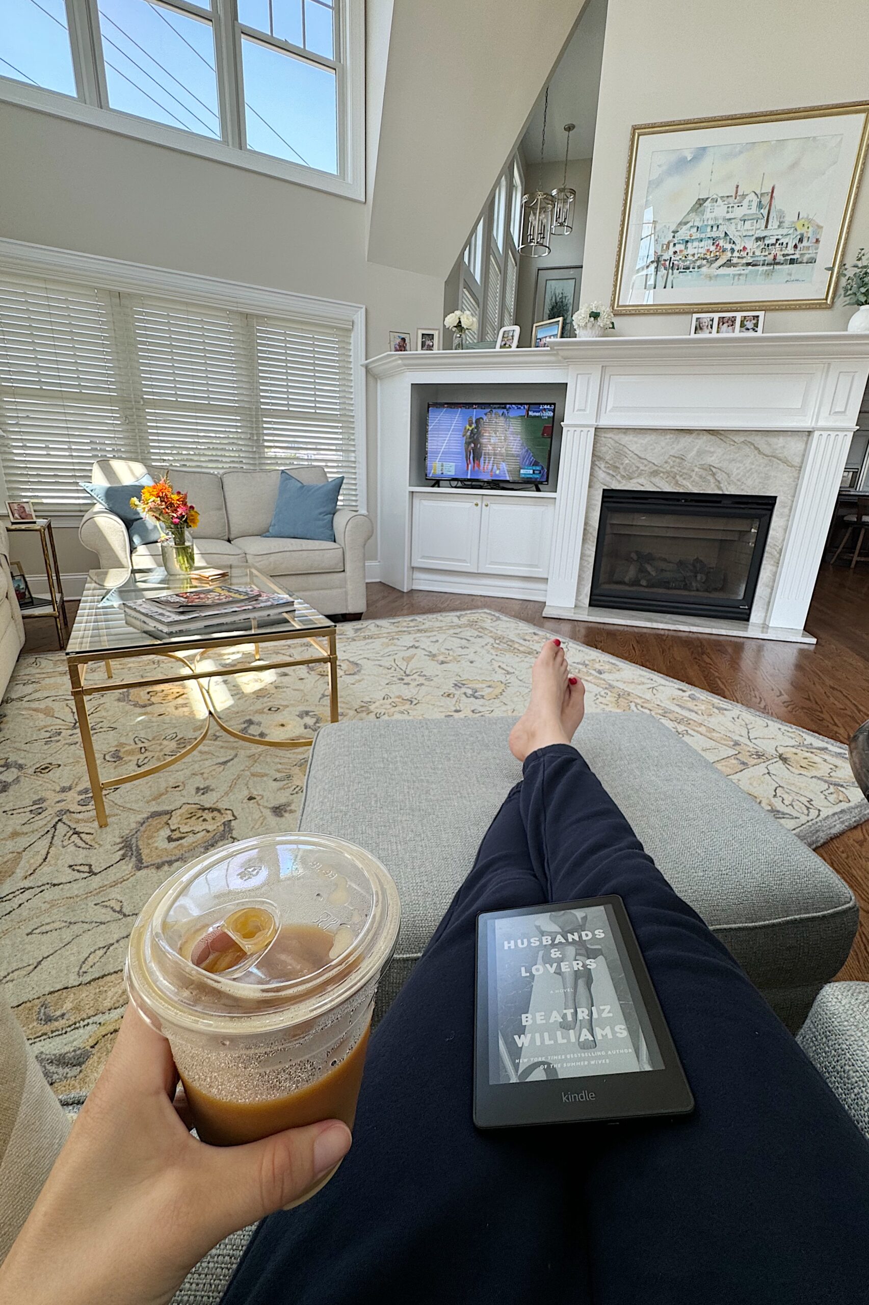 Carly drinking a coffee on the couch with her kindle watching the olympics