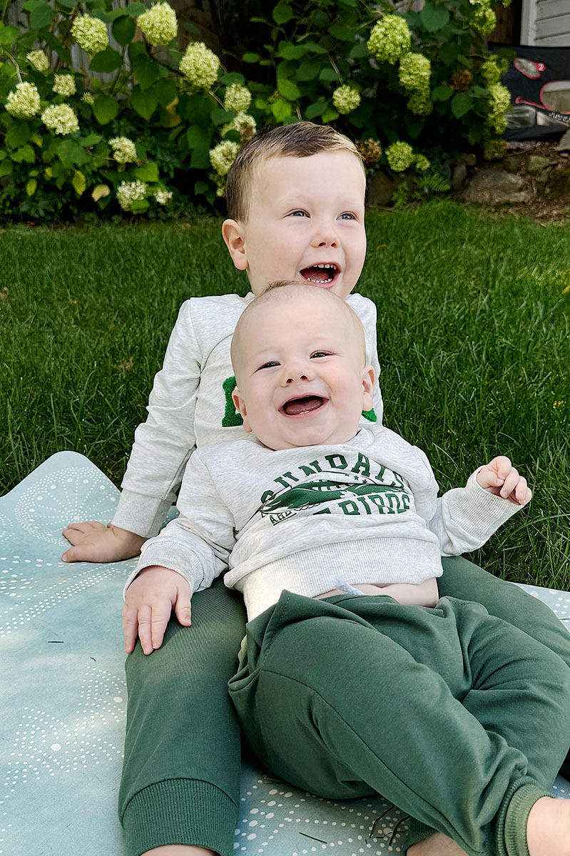 Jack and Rory laying in the grass wearing Eagles sweatshirts