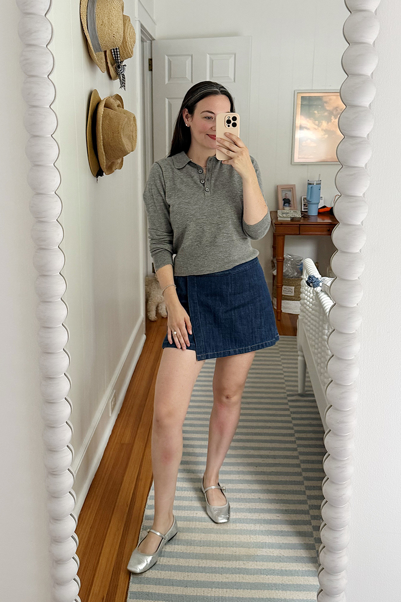 Carly Riordan taking a mirror selfie wearing a grey cashmere polo and denim skort.