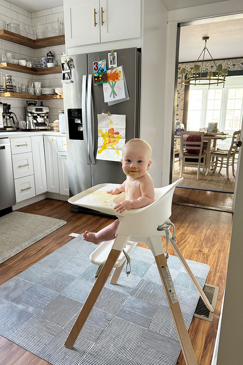 A baby sitting in a high chair in a kitchen