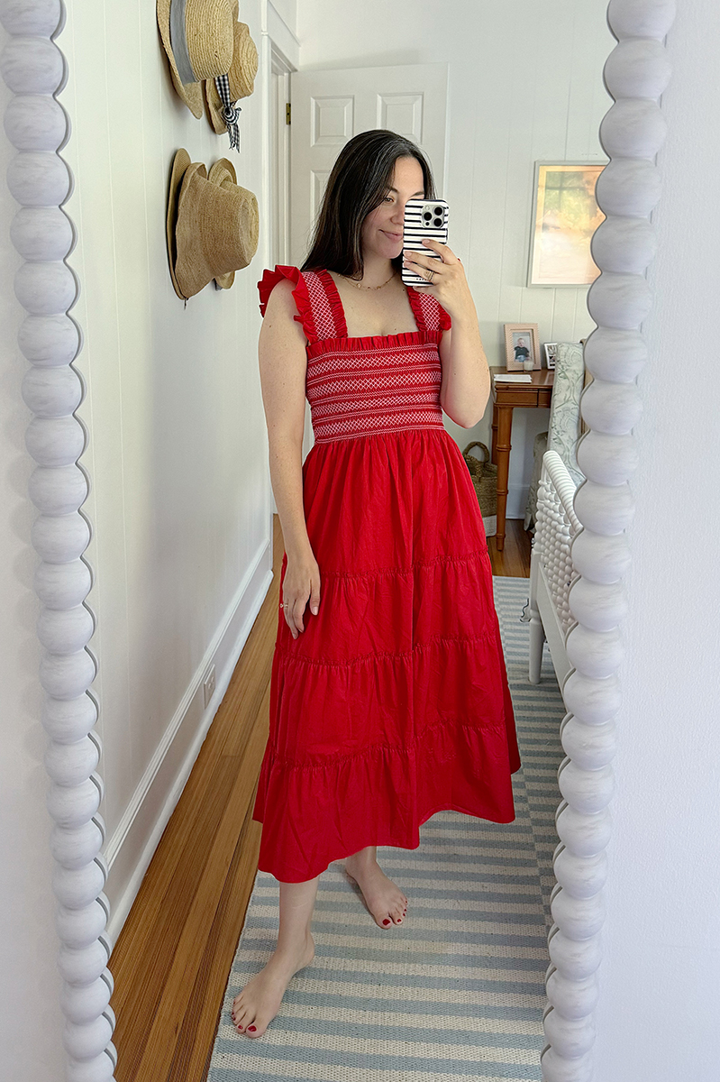 A mirror selfie of Carly wearing a red Hill House nap dress. 