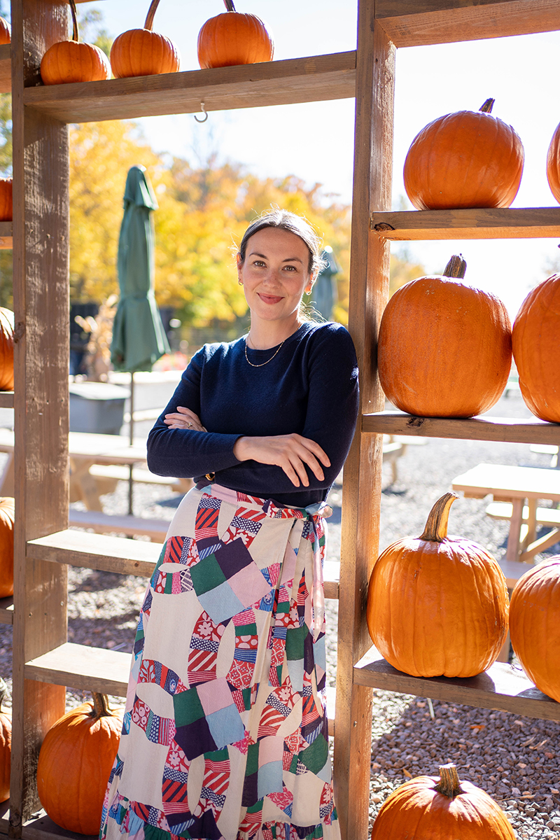 Carly wearing a patchwork skirt and navy sweater in a pumpkin house