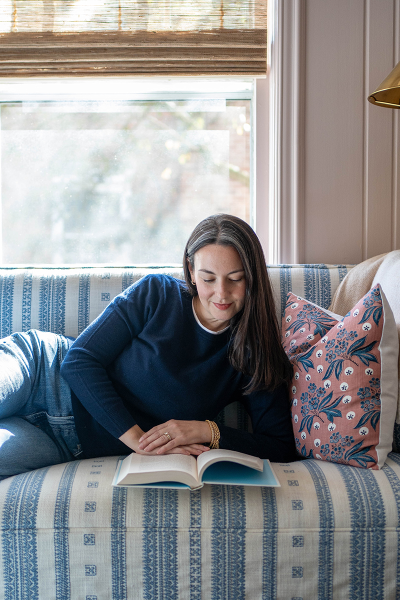 Carly Riordan lounging on a couch reading.