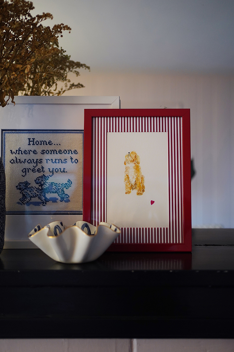 A watercolor portrait of a dog in a red frame