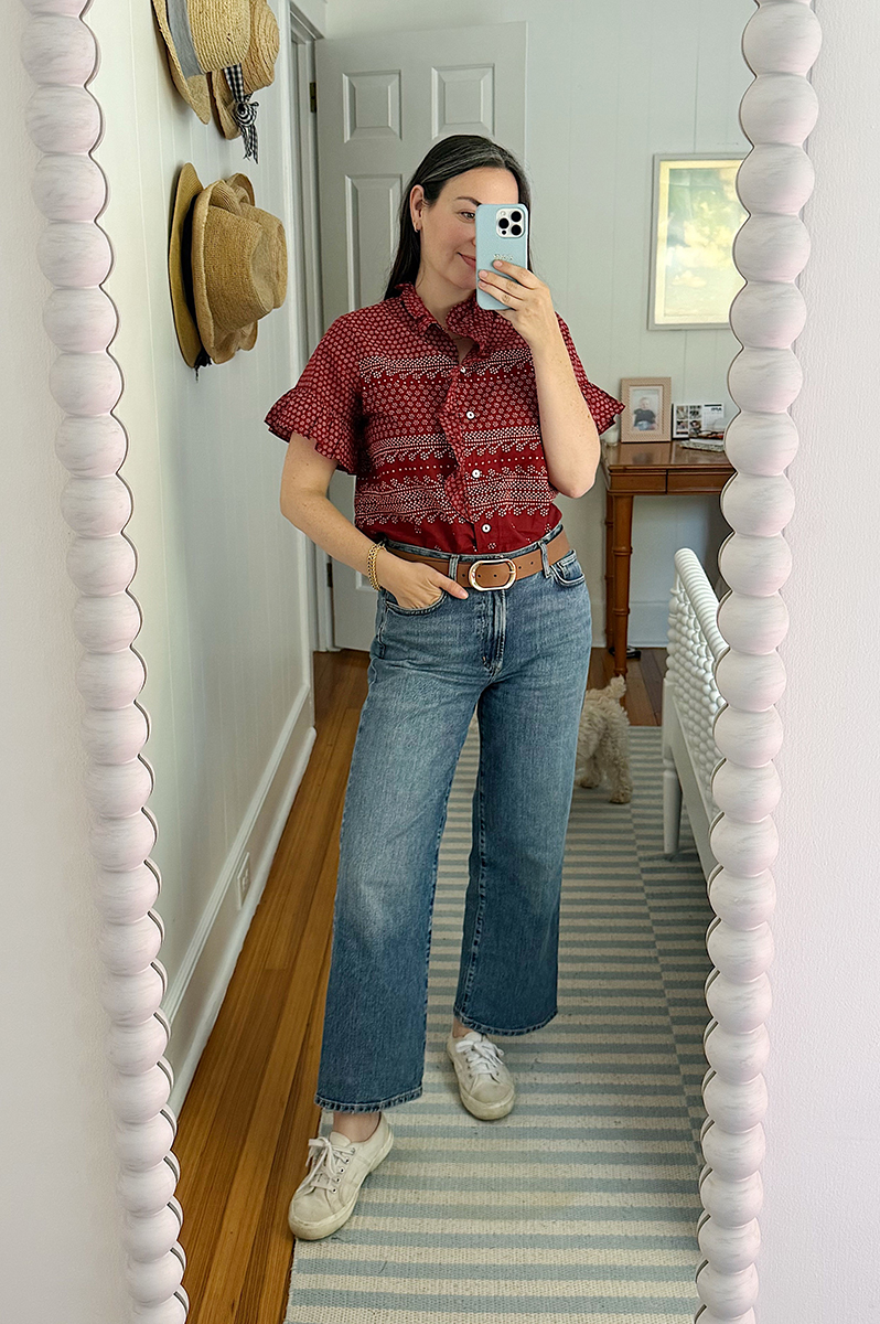 Carly Riordan wearing a raspberry button up and wide legged jeans.