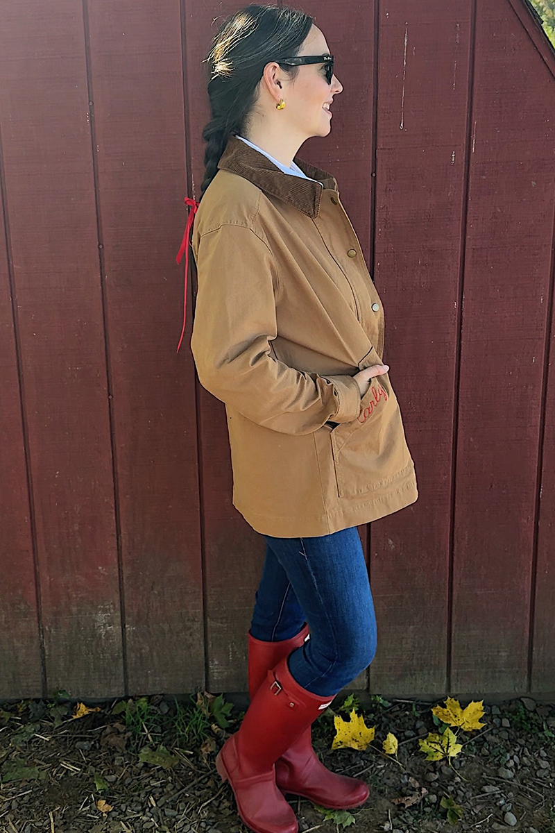 Carly in a mirror selfie wearing a barn coat and red rain boots.