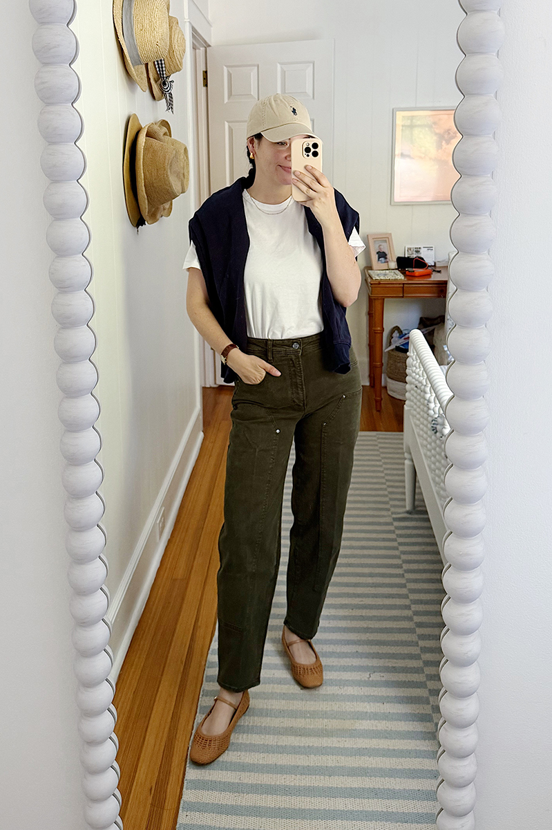 Carly in a mirror selfie wearing a white tee, green pants, and brown mary janes.