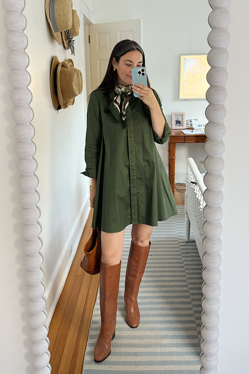 Carly Riordan in a mirror selfie wearing a green dress and tall brown boots.