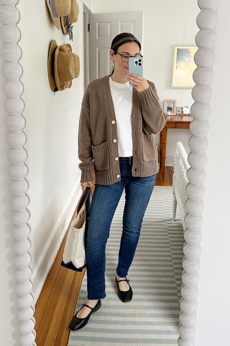 Carly Riordan taking a mirror selfie wearing a cardigan and black mary janes.