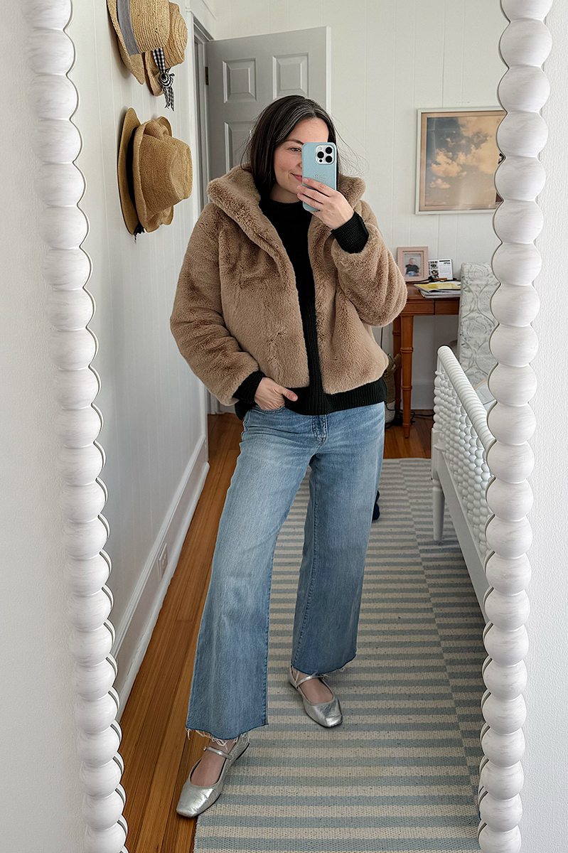 Carly Riordan taking a mirror selfie wearing a faux fur jacket and metallic ballet flats.