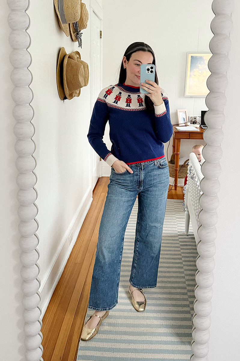 Carly Riordan taking a mirror selfie wearing a fair isle sweater and wide legged jeans.