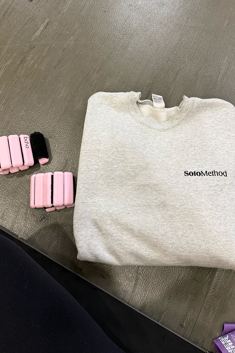 Soto Method Sweatshirt and hand weights on the floor of a gym