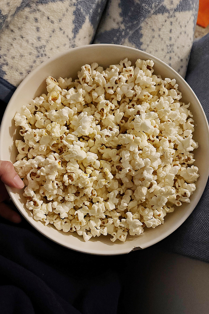 A bowl of stovetop popcorn on a lap