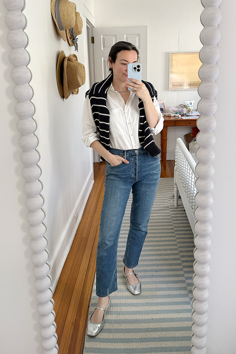 Carly Riordan taking a mirror selfie wearing a striped cardigan over a button down.