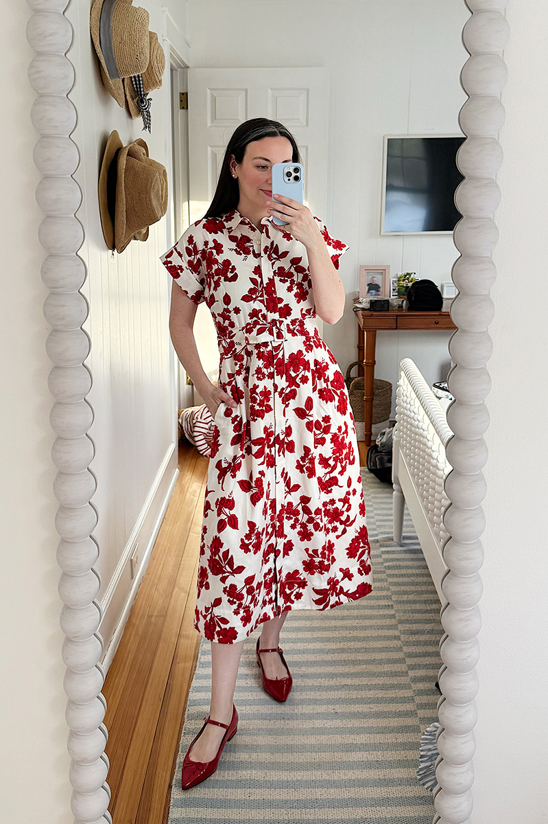 Carly Riordan taking a mirror selfie wearing a red floral shirtdress