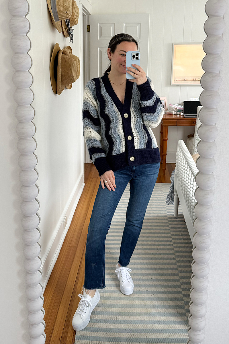 Carly Riordan taking a mirror selfie wearing a cardigan and platform sneakers.