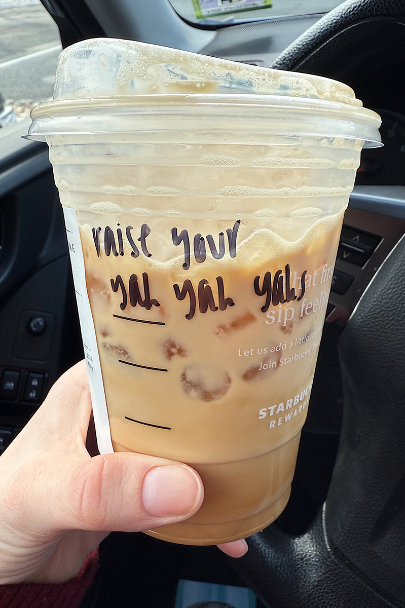 A starbucks iced coffee cup that says "raise your yah yah yahs"