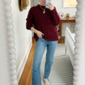 Carly Riordan taking a mirror selfie wearing a burgundy sweater.