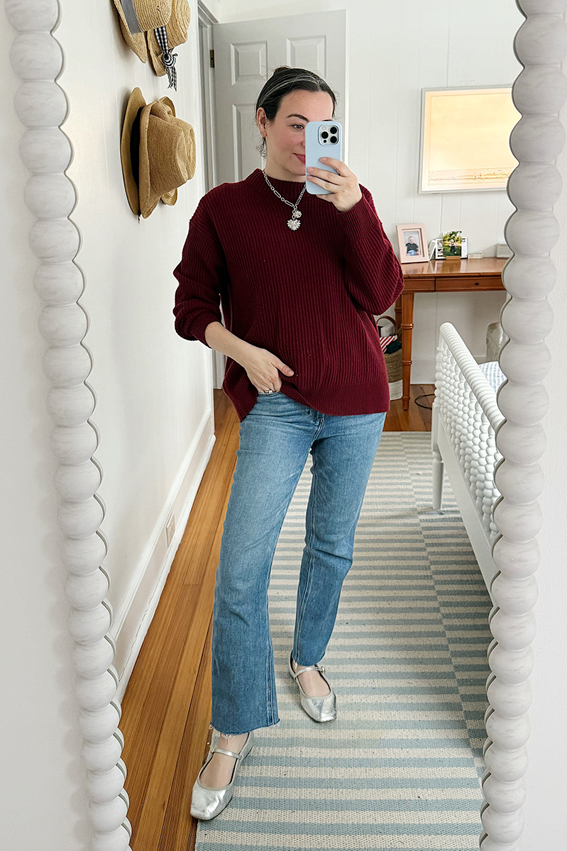 Carly Riordan taking a mirror selfie wearing a burgundy sweater.