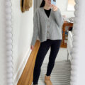 Carly Riordan taking a mirror selfie wearing an oversized cardigan and leggings.